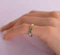 Gold-tone JESSICA band ring with a blue stone worn on a finger