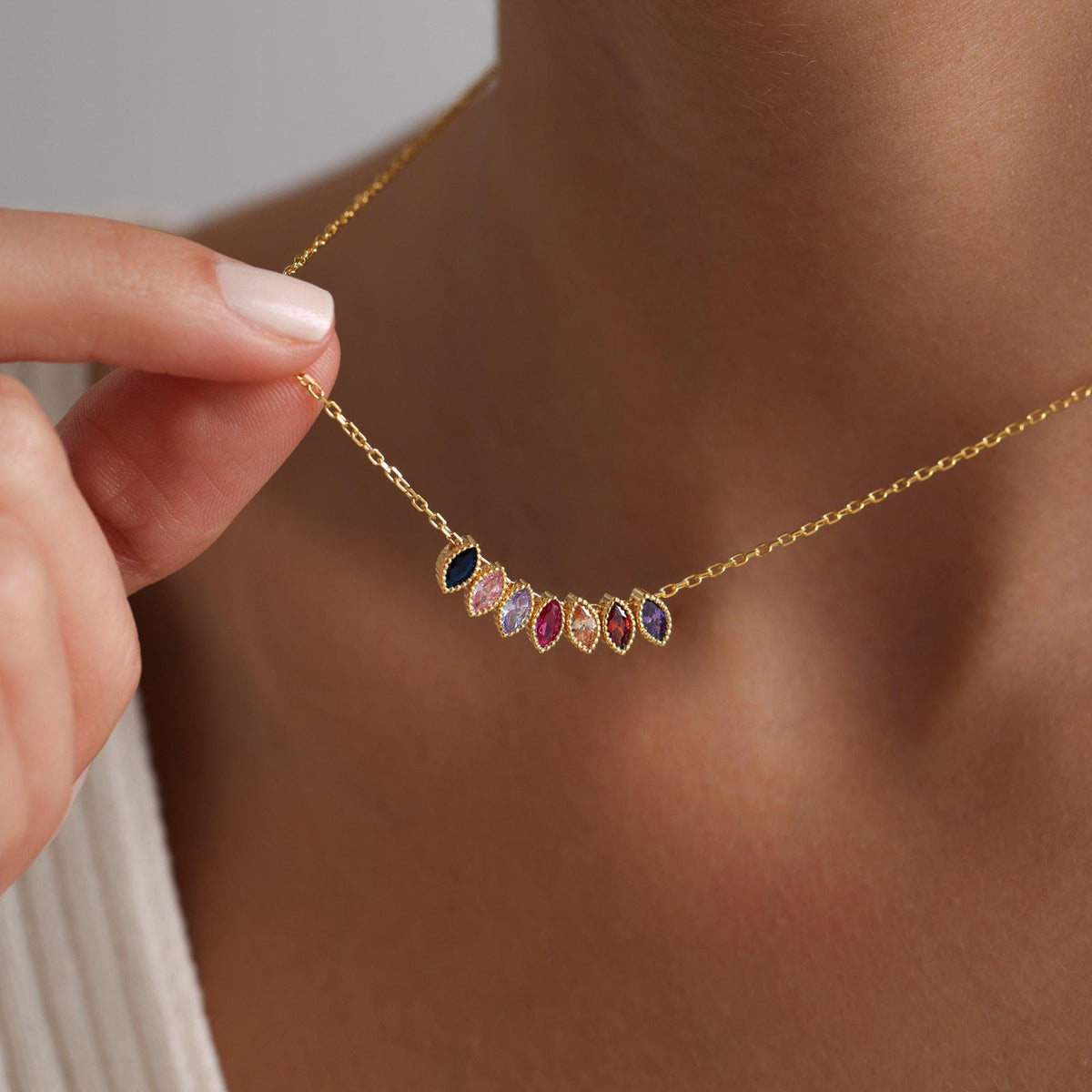 Gold-coloured marquise birthstone necklace held at the neckline