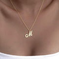Script M initial necklace worn with a white top