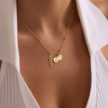 Personalised memorial angel wing necklace in gold vermeil on a satellite chain with an S initial disc and heart disc, worn at the neckline.
