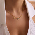 Personalised gold initial necklace with S and K letters and a blue evil eye, worn at the centre of the neckline.