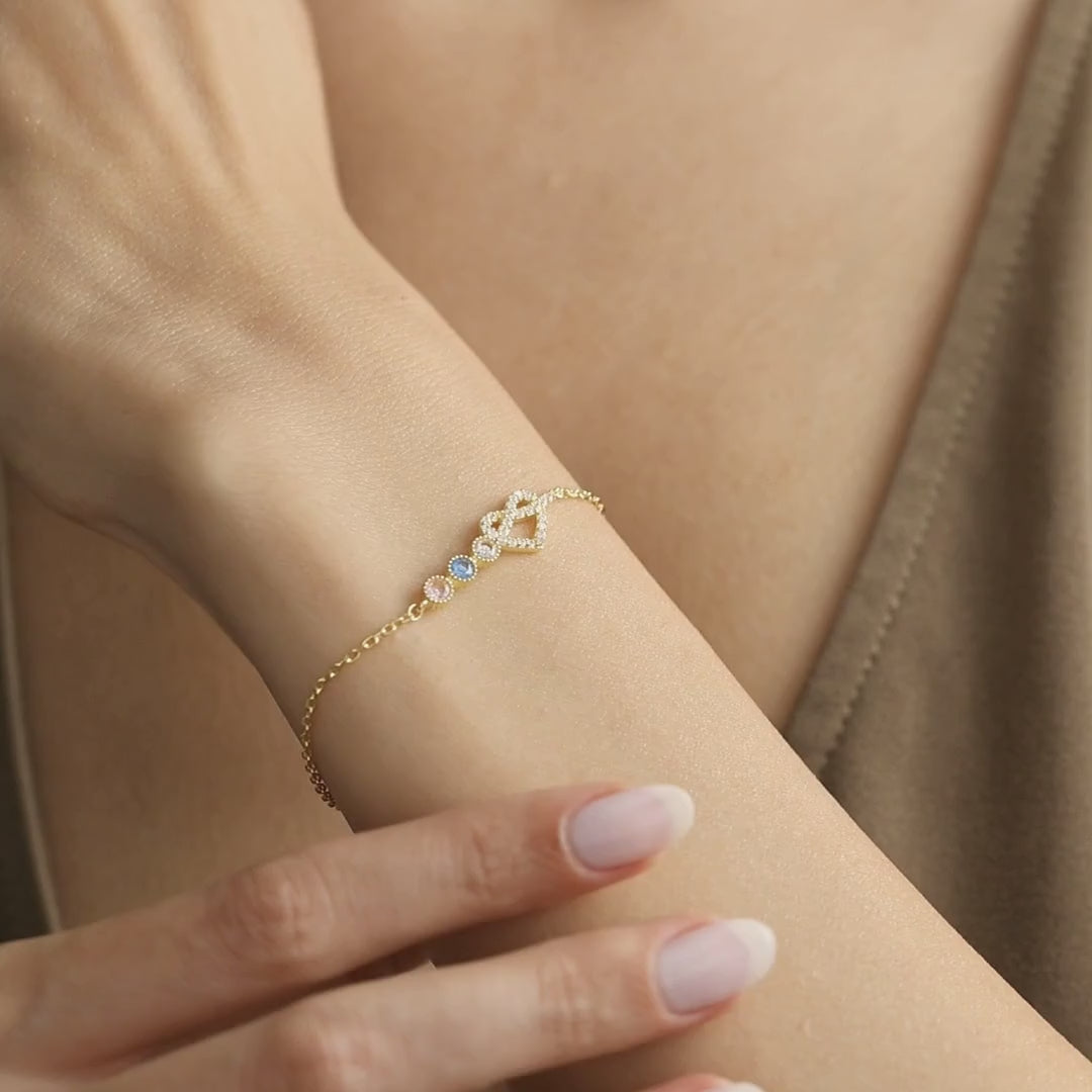 Personalised heart birthstone bracelet shown on the wrist, with a gold vermeil design followed by sterling silver to demonstrate its open-heart detail, colourful stones and movement.