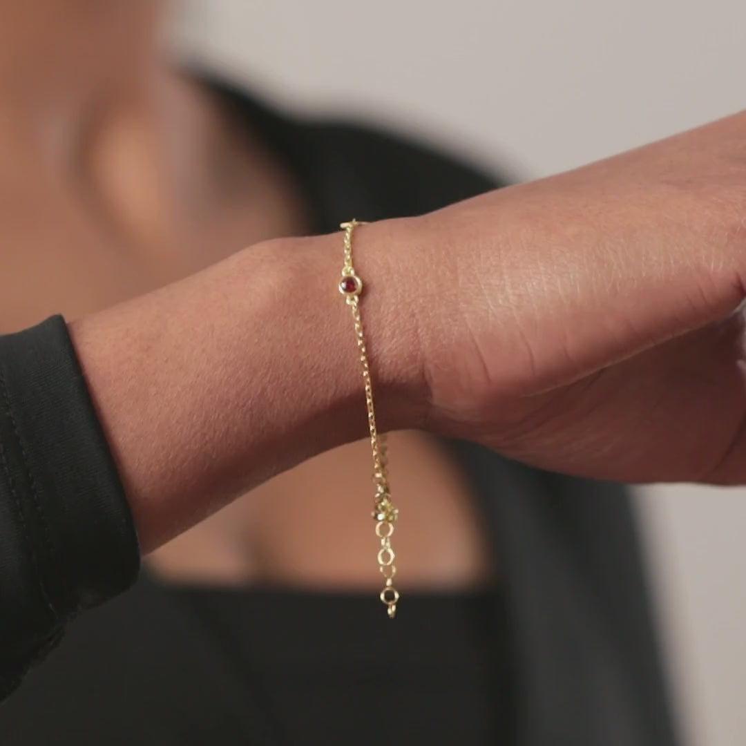 Personalised initial and birthstone bracelet in gold vermeil, shown on the wrist.