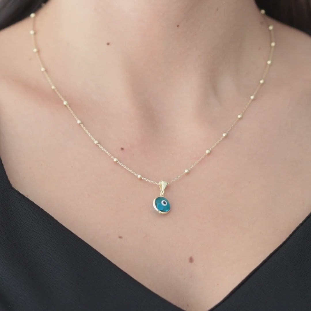 Blue evil eye pendant on a gold vermeil satellite chain, shown worn at the neckline.