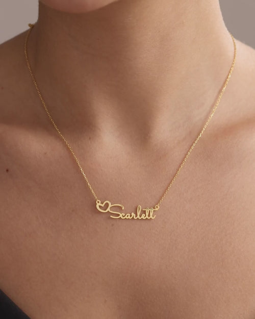 Gold vermeil Scarlett heart name necklace worn at the neckline, showing its lettering, natural movement and scale