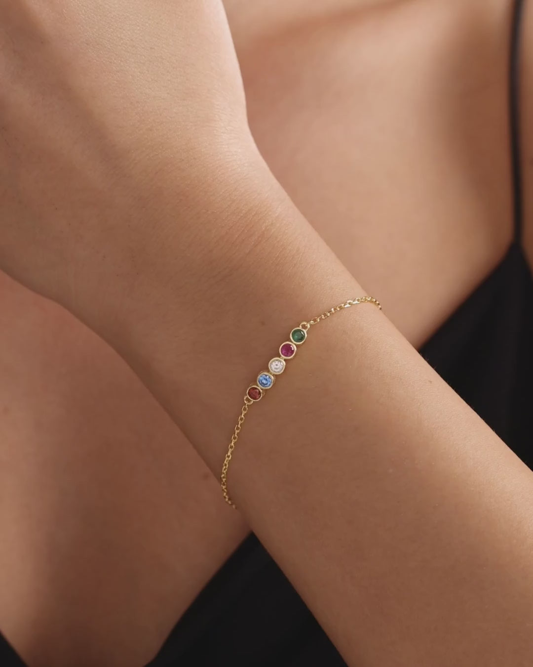 Gold vermeil family birthstone bracelet with round coloured stones worn on the wrist, showing natural movement and scale