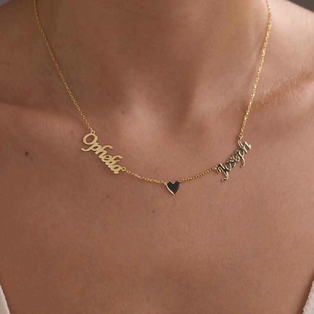 Personalised family name necklace in a gold finish, showing a two-name design with a central heart followed by a five-name design worn along the neckline.
