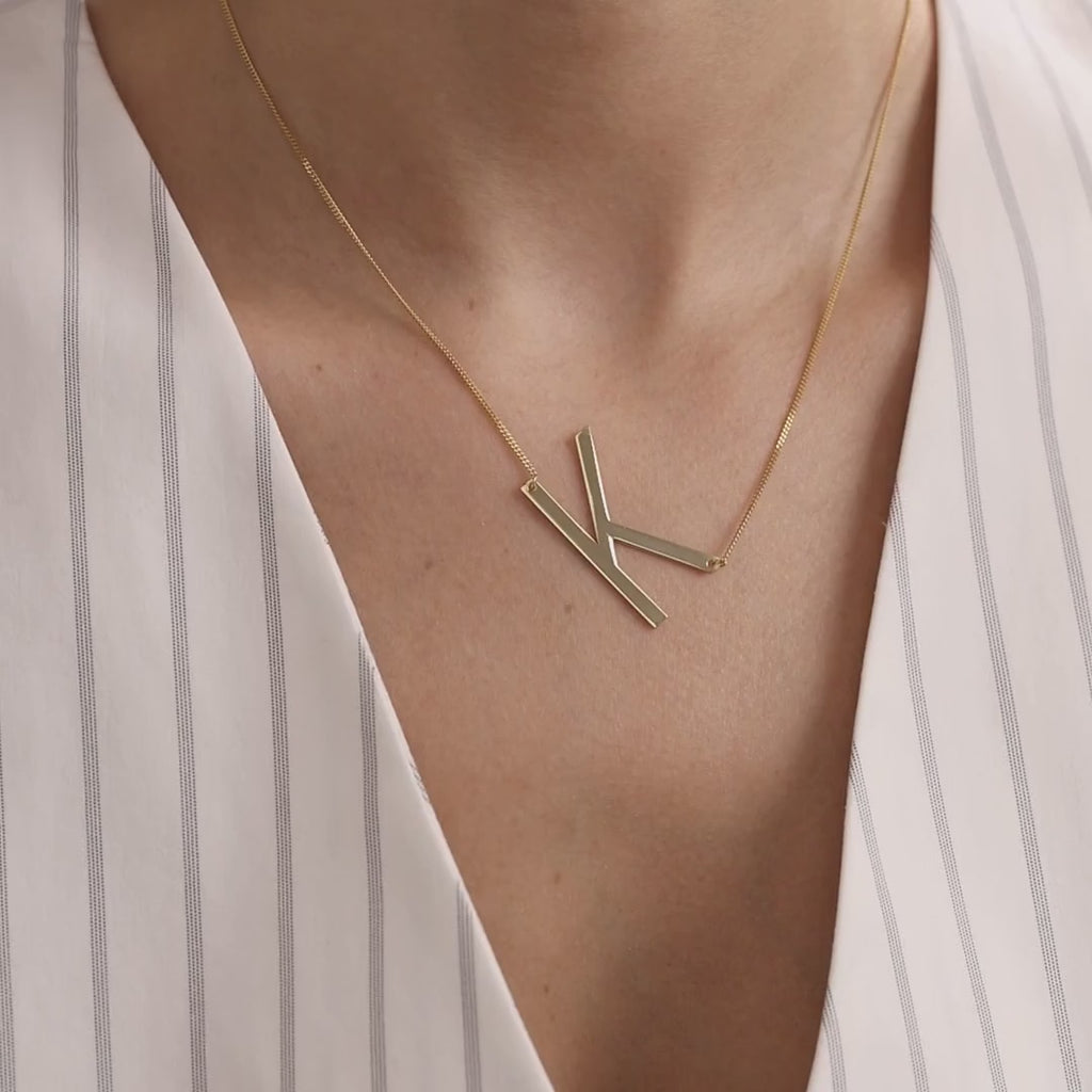 Oversized sideways K initial necklace in gold vermeil worn on a model