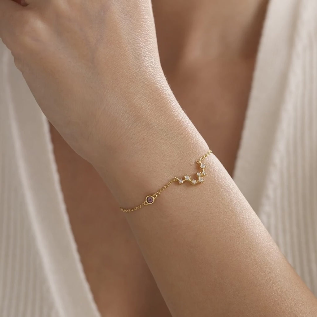 Personalised zodiac constellation bracelet in gold vermeil with a small birthstone accent, shown on the wrist to demonstrate its detail, size and movement.