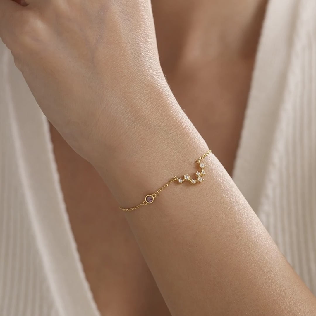 Personalised zodiac constellation bracelet in gold vermeil with a small birthstone accent, shown on the wrist to demonstrate its detail, size and movement.