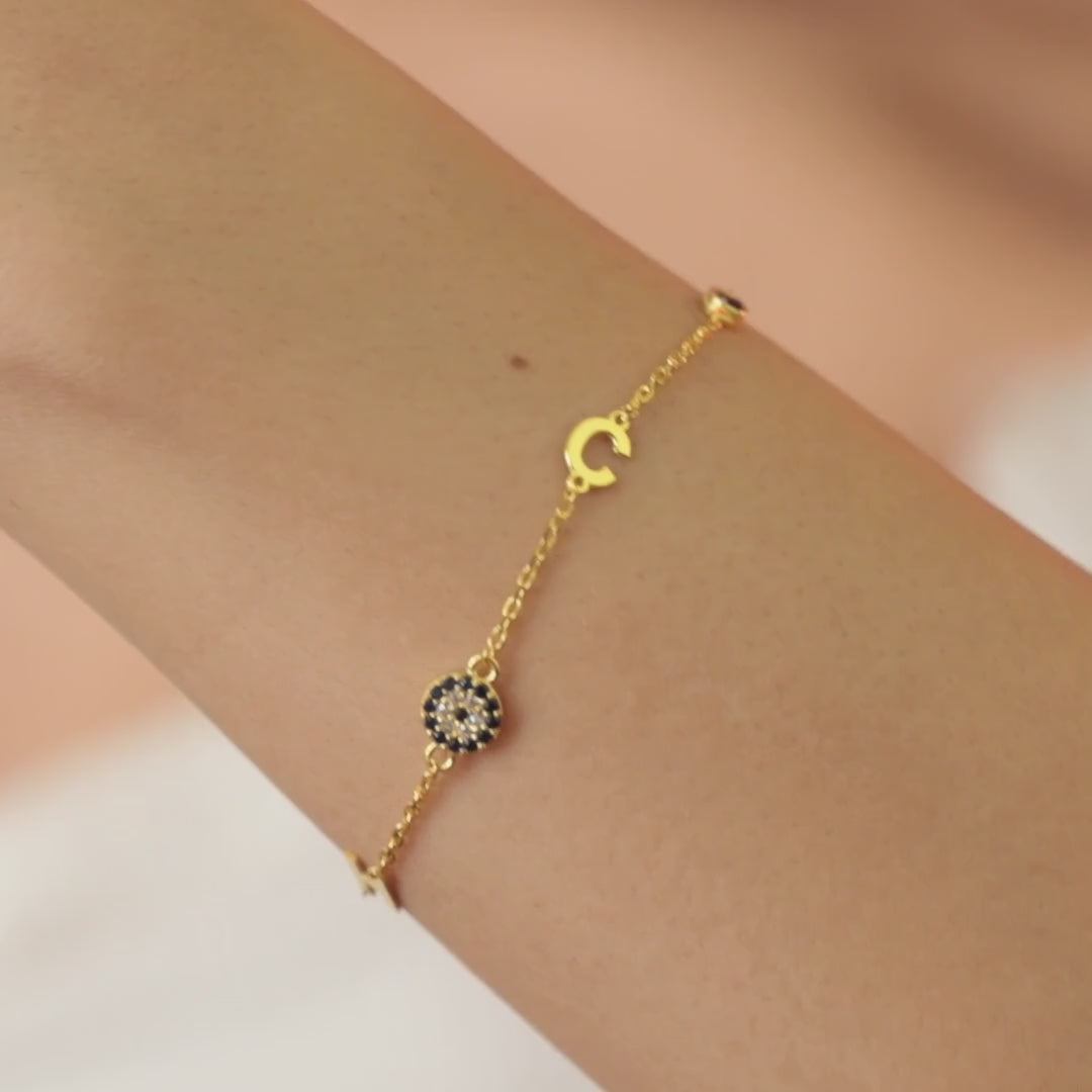 Personalised gold vermeil initial bracelet with an evil eye charm, worn on a wrist