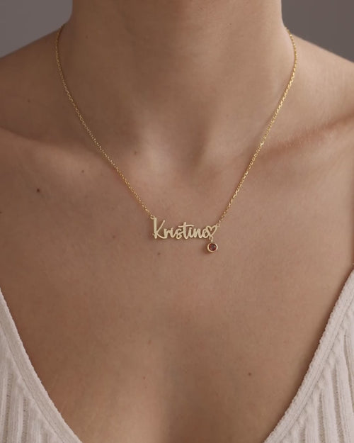 Gold vermeil Kristina name necklace with a birthstone charm worn on the neckline, showing its natural movement and scale