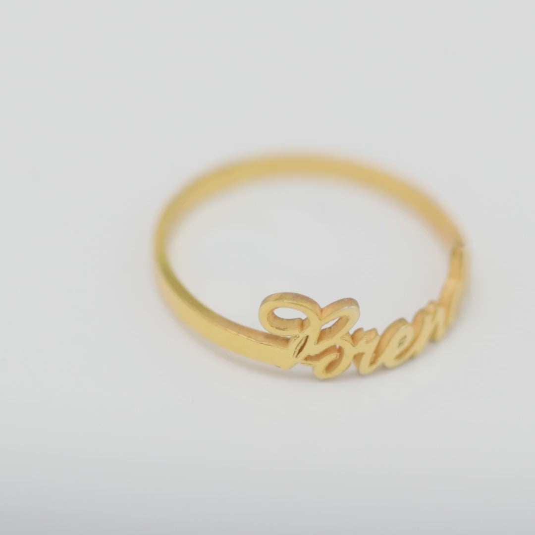 Personalised gold vermeil name ring with Brenda lettering, close-up on a light background