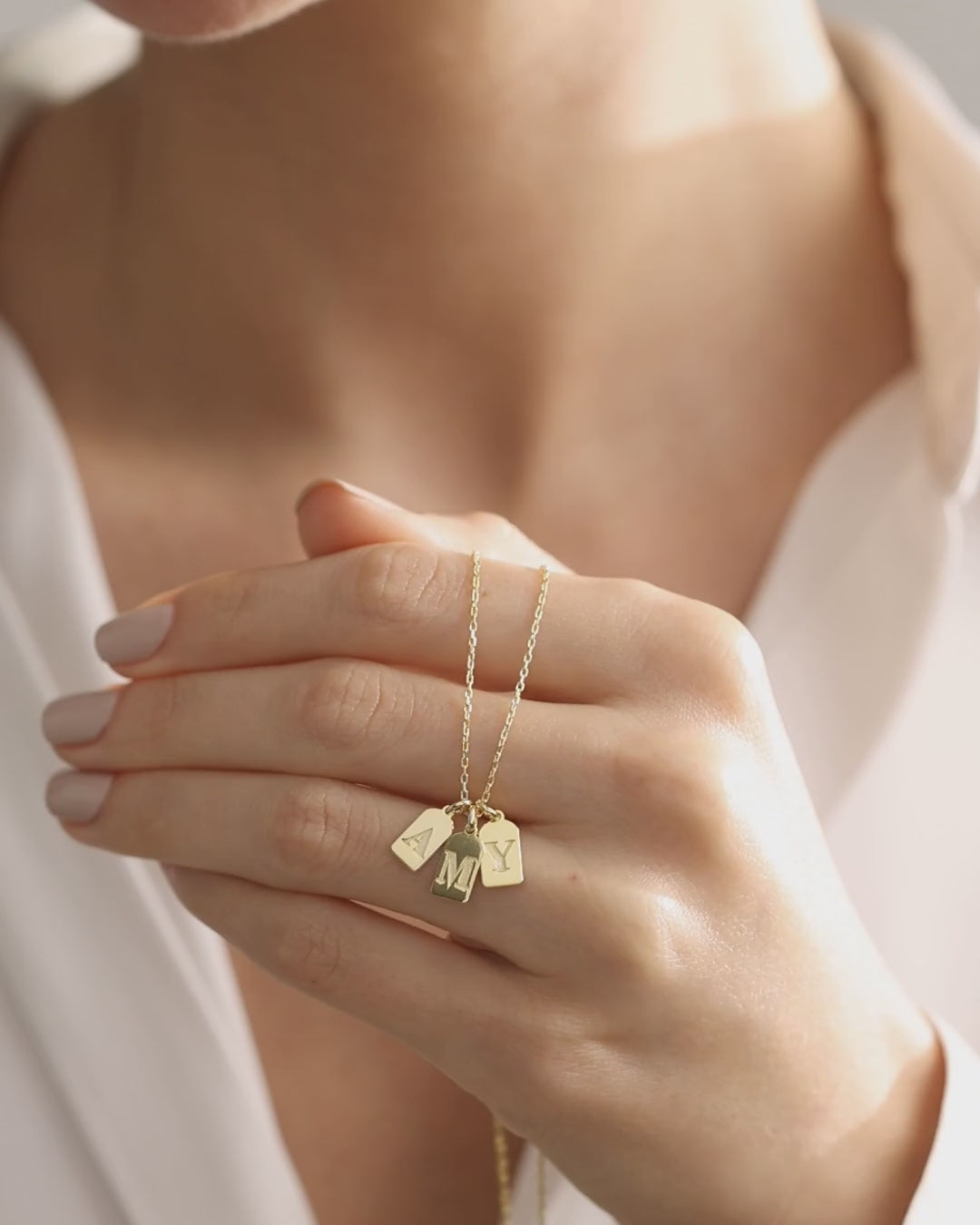 Family initial tag necklace: gold vermeil multiple initial charms shown in detail, followed by a sterling silver single initial necklace worn at the neckline