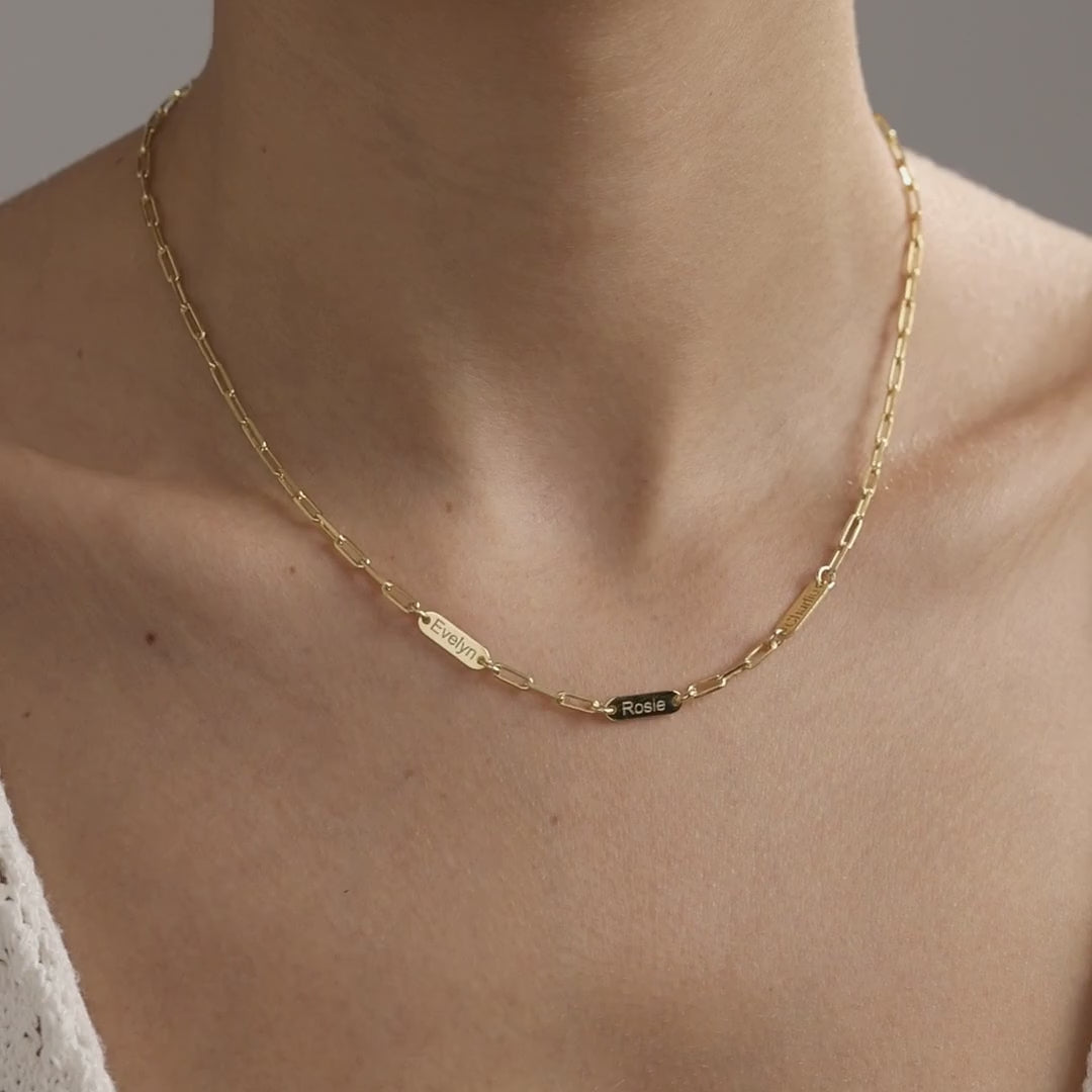 Personalised family name bar necklace with engraved bars on a paperclip chain, shown in gold vermeil followed by sterling silver, worn at the neckline.