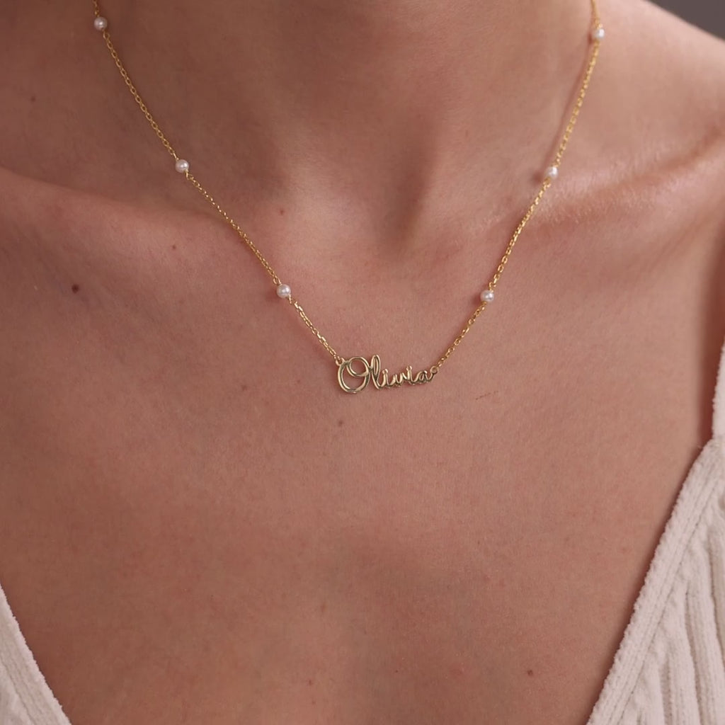 Personalised name necklaces worn at the neckline: Olivia on a gold pearl satellite chain, Amelia on a gold satellite chain, and Samuel on a silver paperclip chain.
