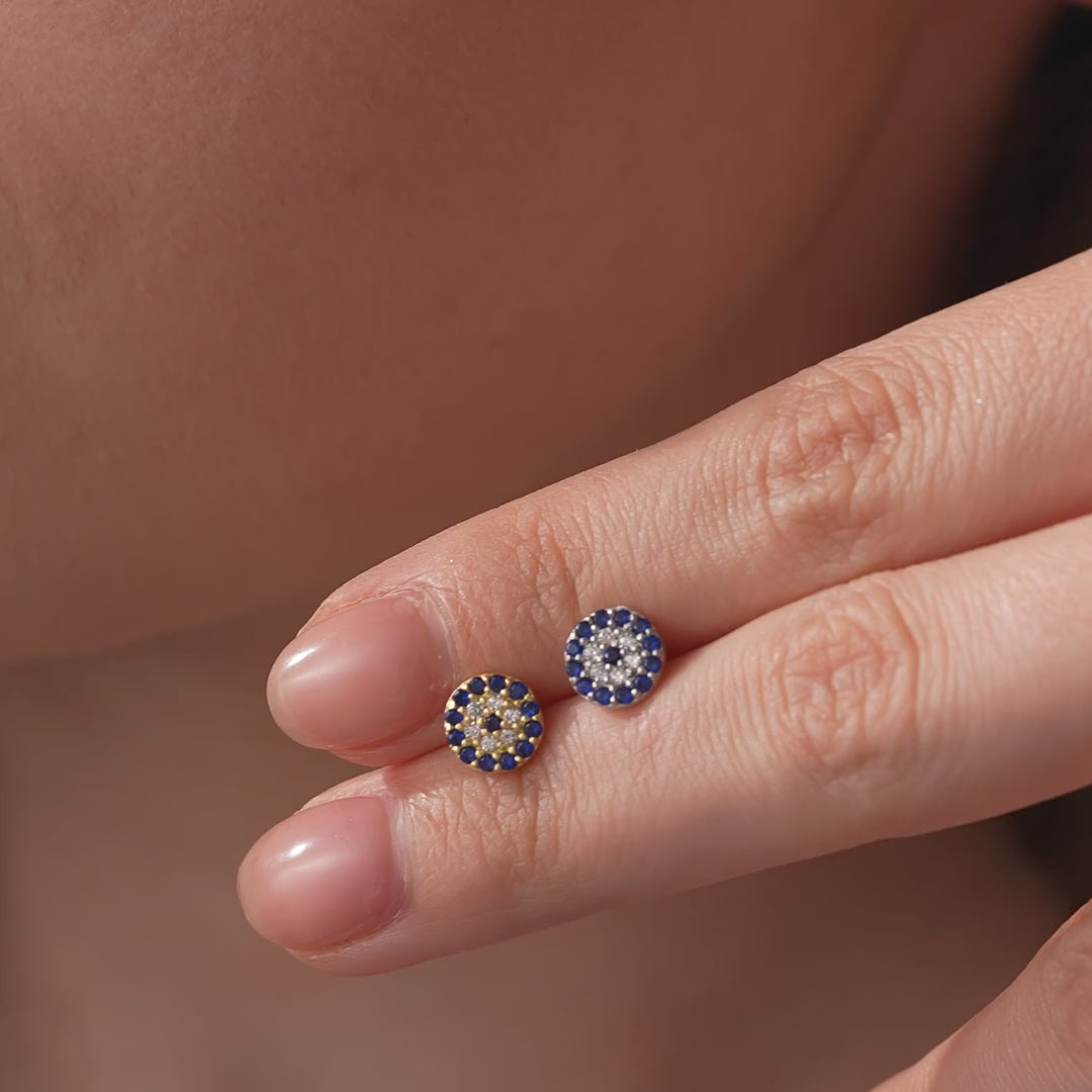 Evil eye stud earrings in gold vermeil and sterling silver shown close up on fingertips, followed by the gold earring worn on the ear.