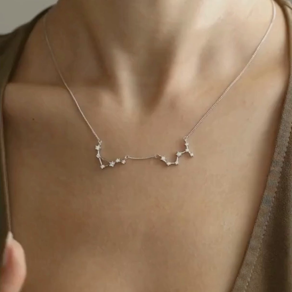 Zodiac constellation necklaces on curb chains in sterling silver and gold vermeil, worn on a model