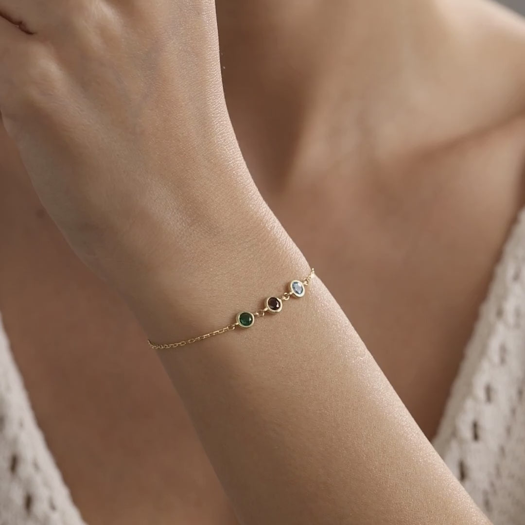 Custom family birthstone bracelet shown on the wrist, with a three-stone gold vermeil design followed by a five-stone sterling silver design.