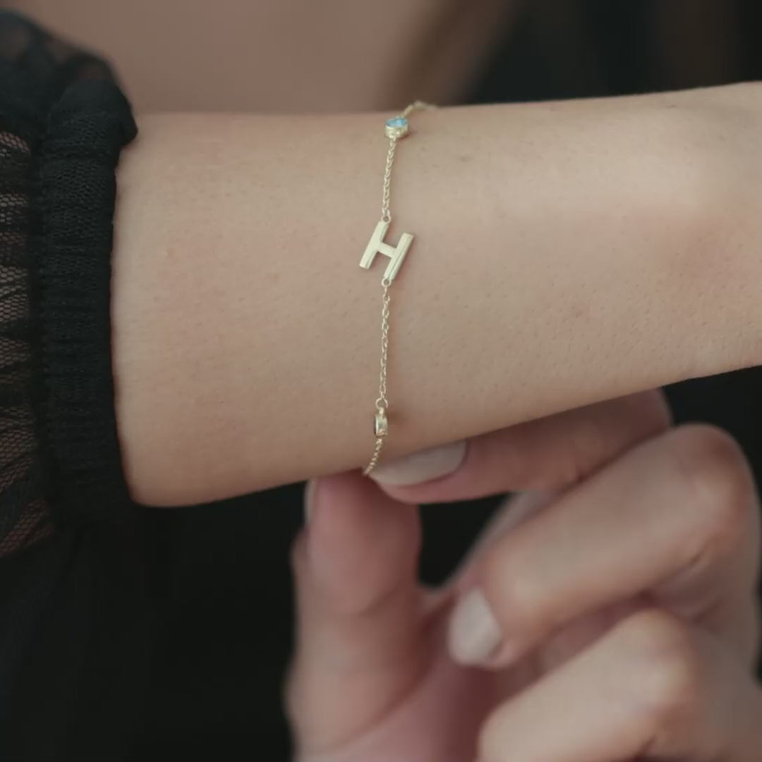 Initial and blue birthstone bracelet worn on a wrist, shown close up in a square video with framing that follows the bracelet