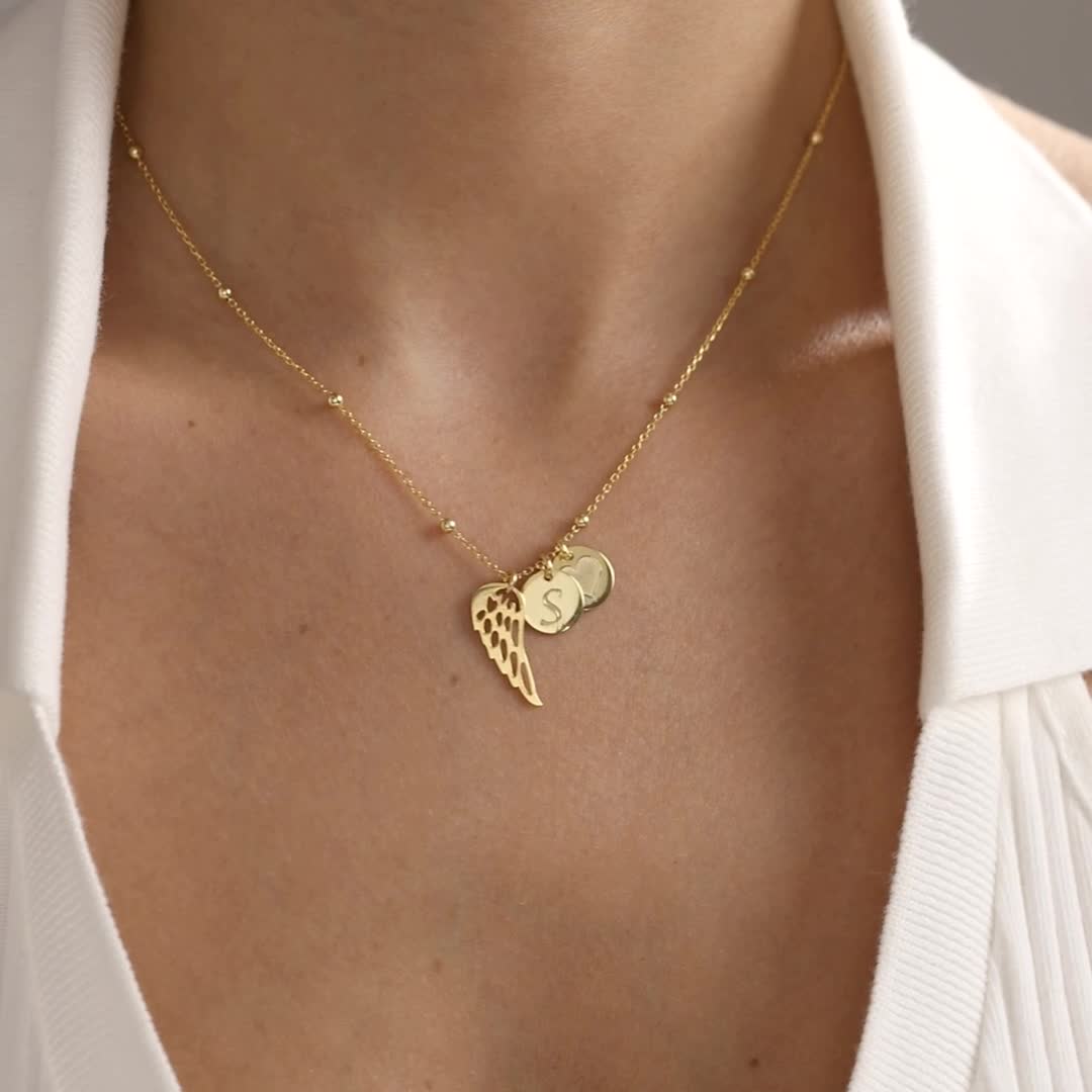Personalised Memorial Angel Wing Necklace with engraved initial discs, shown worn in gold vermeil and sterling silver finishes.