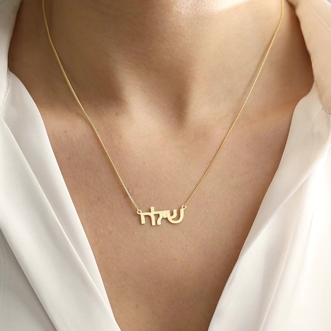 Personalised Hebrew Name Necklace in 14K gold vermeil, showing the Hebrew lettering worn and held close up.